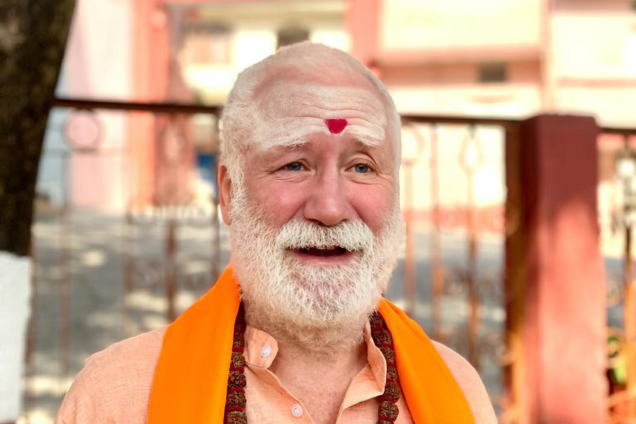 Swami Brahmananda smiling outdoors in orange robes
